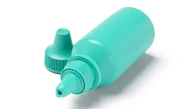 Teal eye drop bottle, uncapped, lying on its side against a white background.